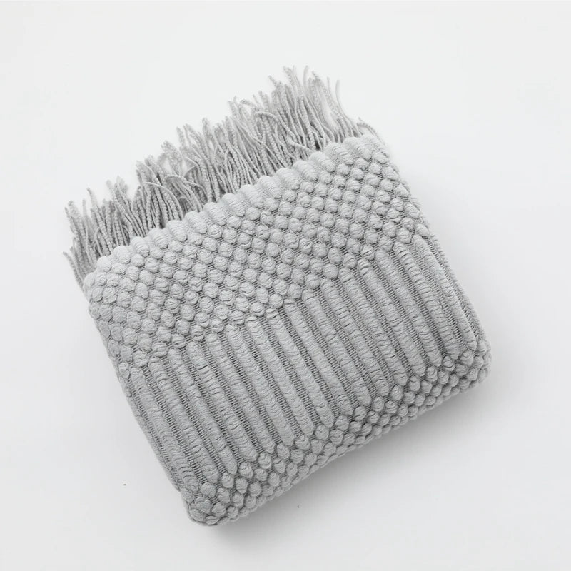 Gray textured blanket with fringe on a white background