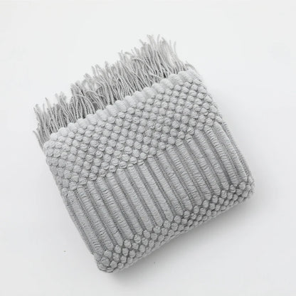 Gray textured blanket with fringe on a white background