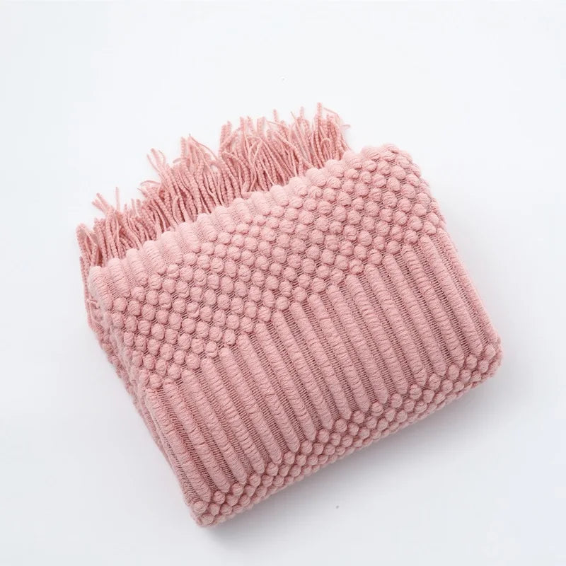 Pink textured blanket with fringe on a light gray background