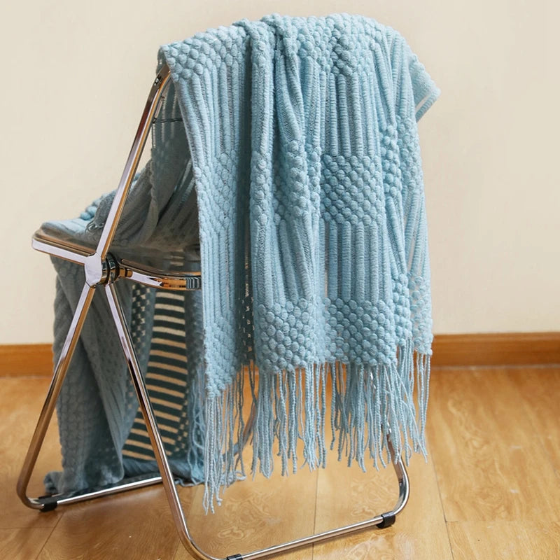 Light blue textured throw blanket draped over a metal chair on a wooden floor.