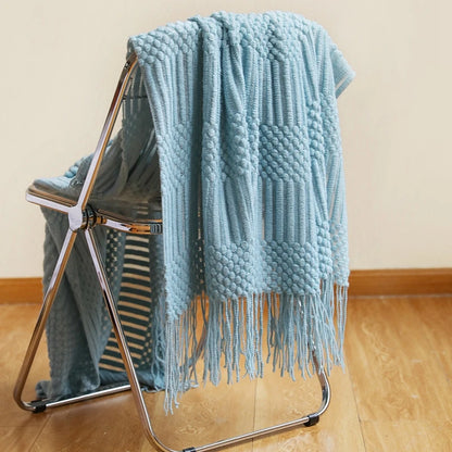 Light blue textured throw blanket draped over a metal chair on a wooden floor.