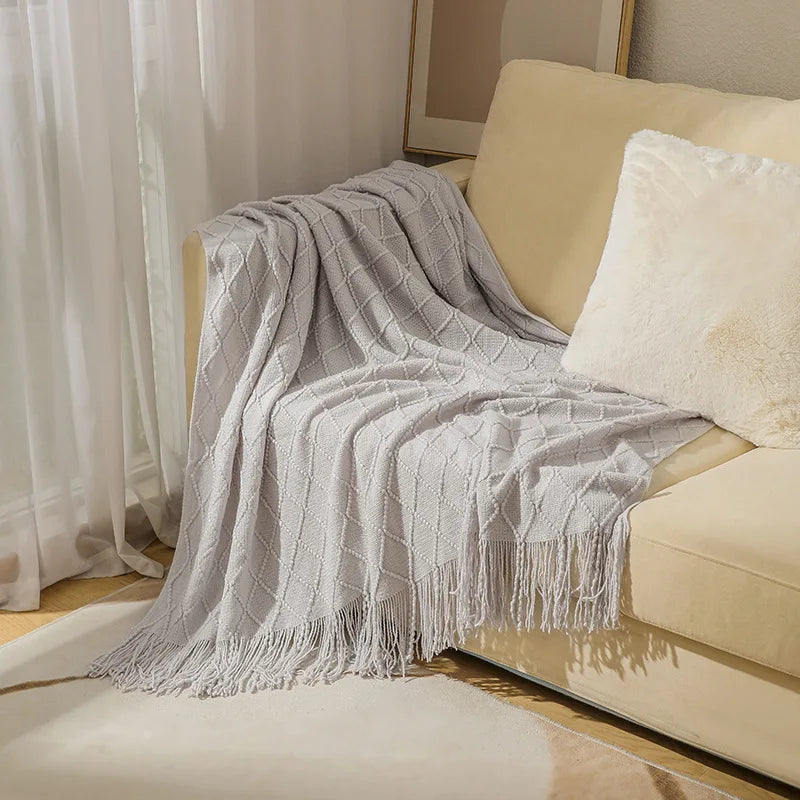 Gray textured throw blanket draped over a beige sofa with a neutral background