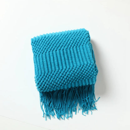 Blue knitted throw blanket with fringe on a white background
