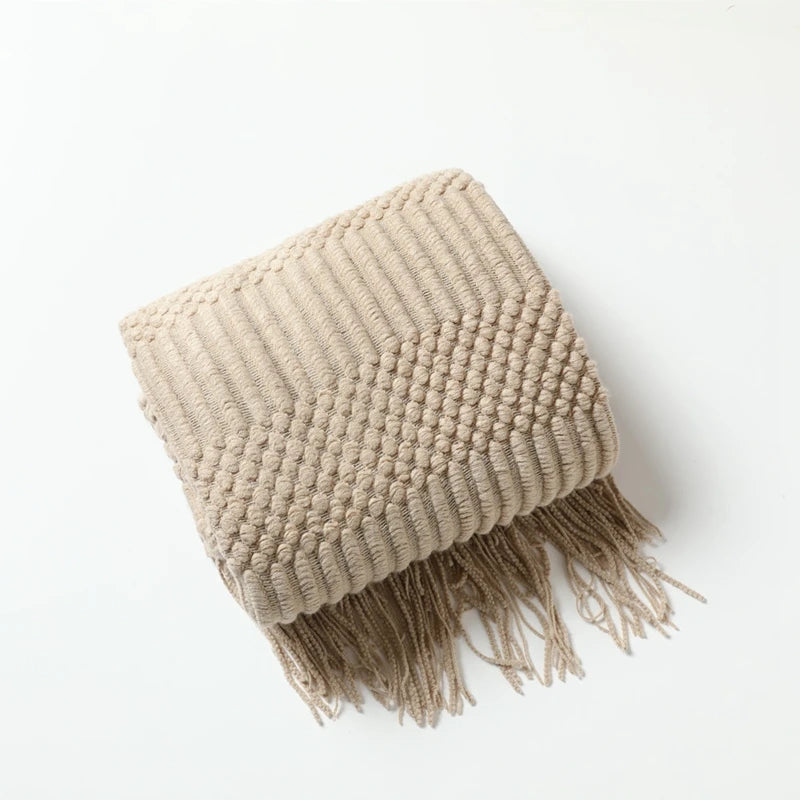 Beige knitted throw blanket with fringes on a white background