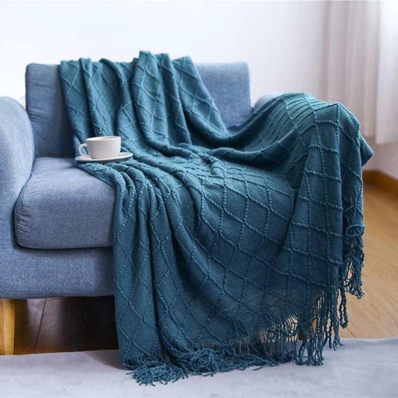 Teal blanket draped over a gray sofa with a white cup on a saucer.