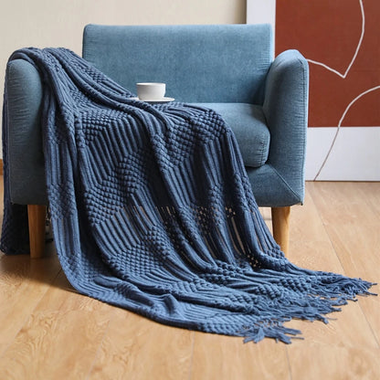 Blue textured throw blanket draped over a blue armchair on a wooden floor.