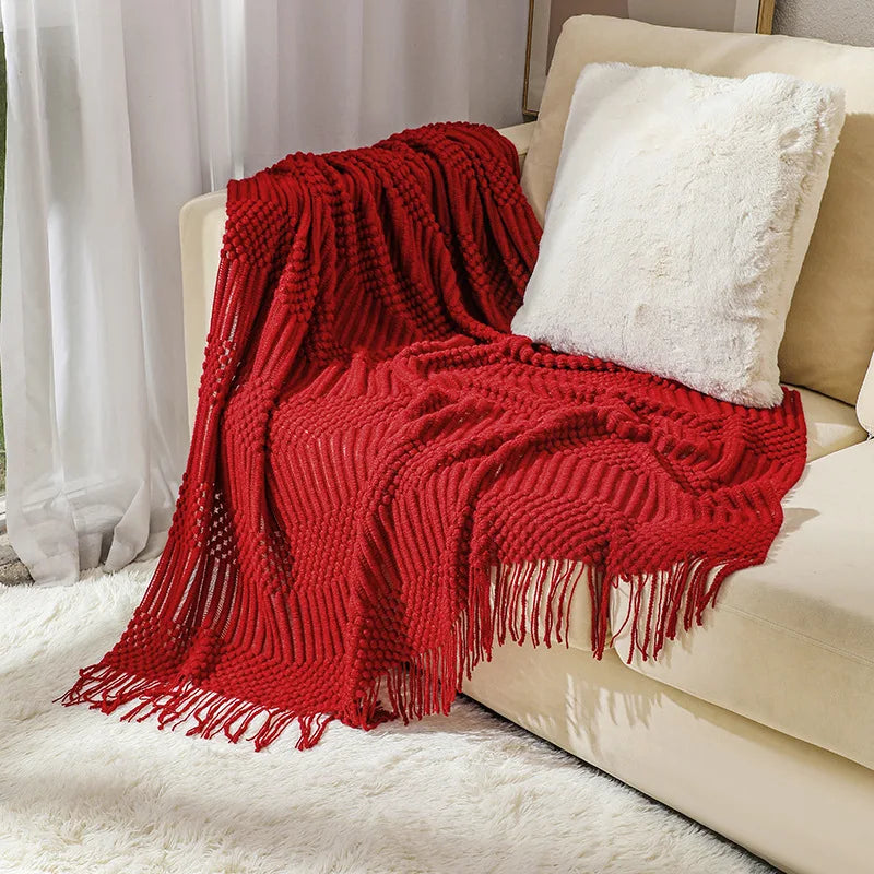 Red knitted blanket draped over a beige sofa with a white pillow.