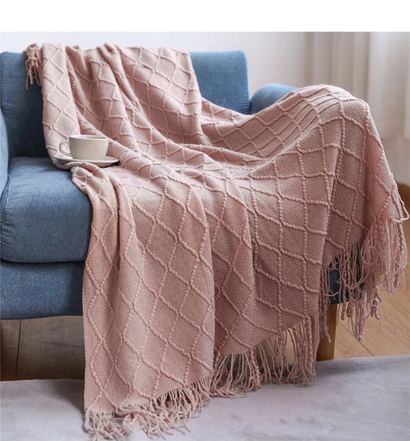 Pink textured throw blanket draped over a blue sofa with a white cup on a saucer.