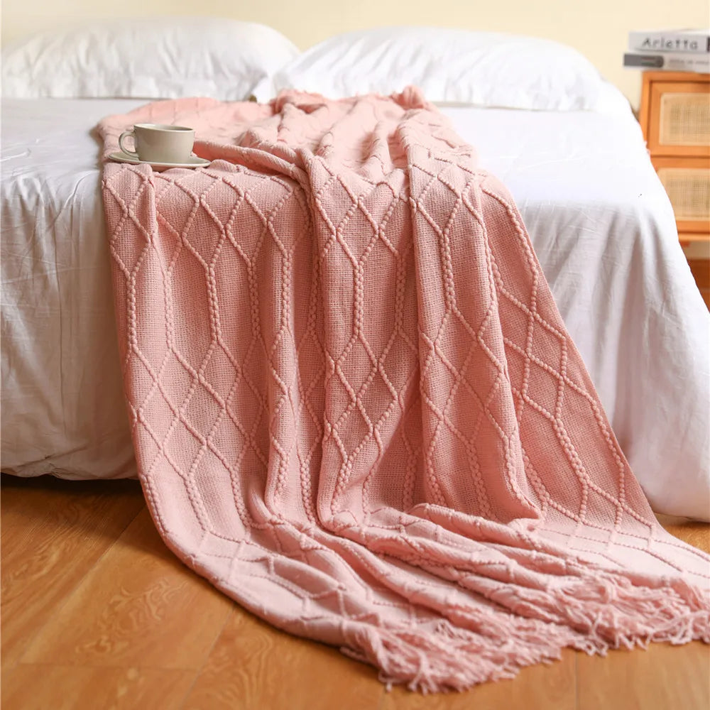 Pink textured blanket draped over a bed with a wooden headboard.