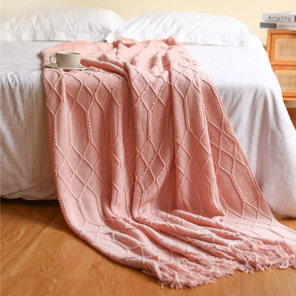 Pink textured blanket draped over a bed with a wooden headboard.