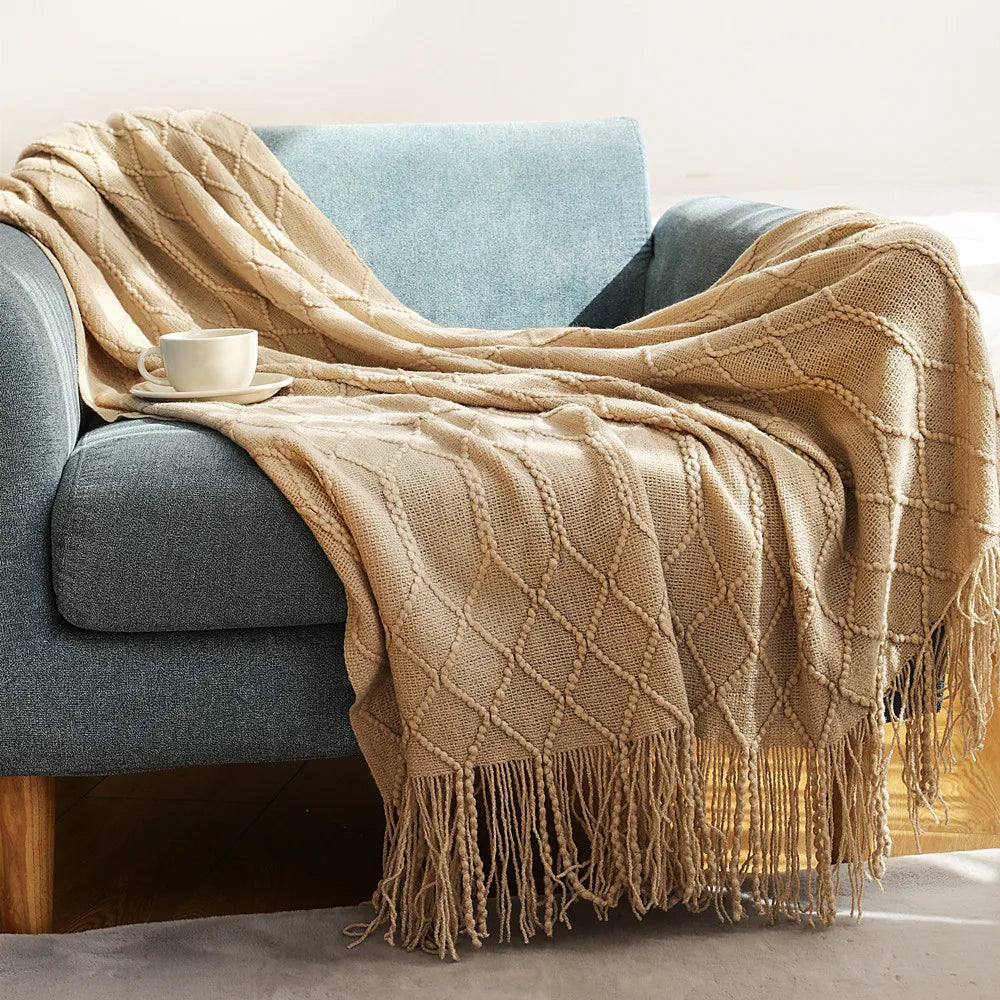 Beige blanket draped over a gray sofa with a cup on a small table.