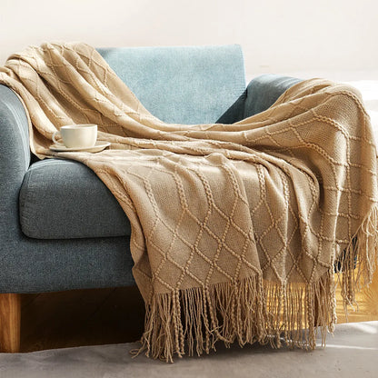 Beige blanket draped over a gray sofa with a cup on a small table.