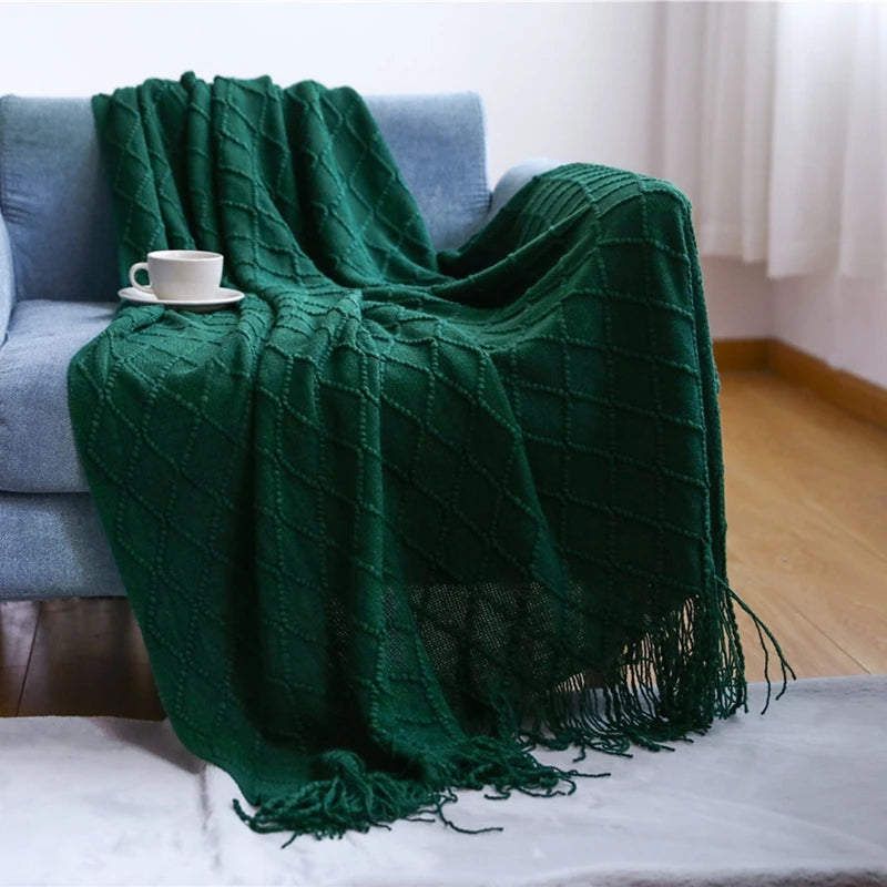 Green textured blanket draped over a couch with a cup on a small table.