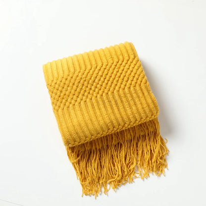 Yellow knitted blanket with fringes on a white background